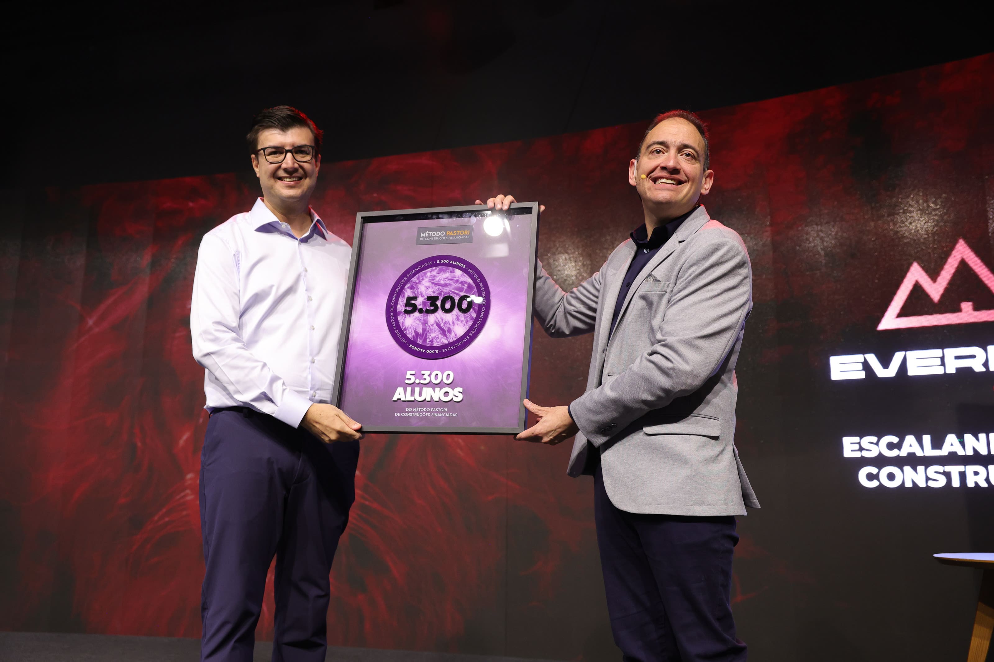 Fernando com gesto largo no palco, energia comercial